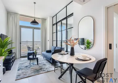 a living room with a table and a blue couch at Stunning 1BR in Dubai Hills in Dubai