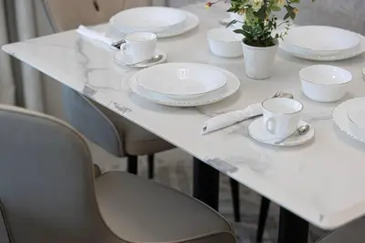 a white table with white plates and cups and chairs at 2 BR Dubai Luxury apartment Full Burj Views in Dubai