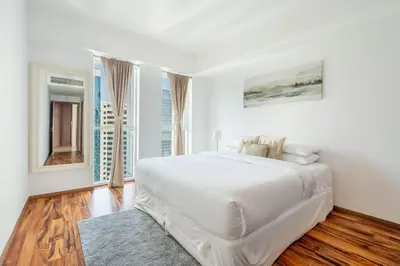 a white bedroom with a large white bed and wood floors at GuestReady - Home away from home in JLT in Dubai