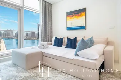 a living room with a couch and a large window at LUX The Bays Edge Canal View Suite in Dubai