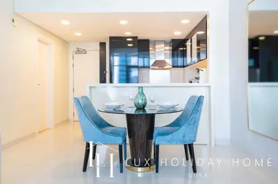 a dining room with a table and blue chairs at LUX The Bays Edge Canal View Suite in Dubai