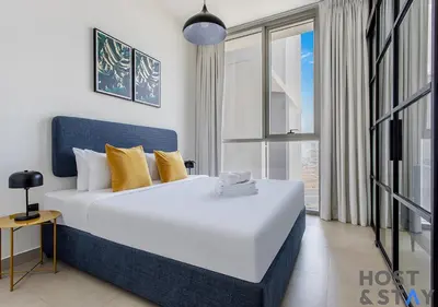 a bedroom with a large white bed with yellow pillows at Lux 1BR Near Dubai Hills Mall in Dubai