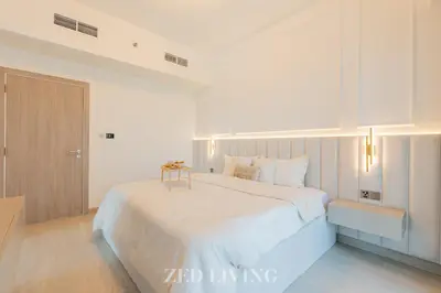 a white bedroom with a large bed and a door at Me Do Re - Luxury Living 1 BR with Panoramic View - Zed Living in Dubai