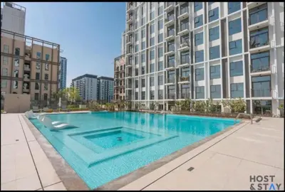 a large swimming pool in front of a tall building at Elegant 1BR In Collective, Dubai Hills in Dubai