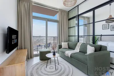 a living room with a green couch and a large window at Modern 2BR Gem In Dubai Hills in Dubai