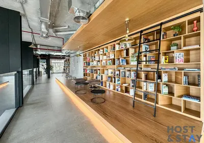a library with wooden shelves and two chairs and books at Serene 1BR Getaway In Collective in Dubai