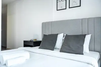 a bed with white sheets and gray pillows at ShoresInn - Spacious unit with Dubai Marina View in Dubai
