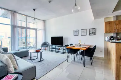 a living room with a couch and a table with chairs at ShoresInn - Spacious unit with Dubai Marina View in Dubai