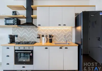 a kitchen with white cabinets and a black refrigerator at Stylish 1BR Apt In Collective 2 in Dubai