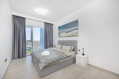 a white bedroom with a bed and a large window at Medore Brand New Flat in Dubai - 8 in Dubai