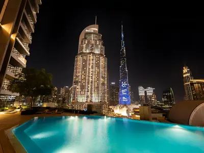 a swimming pool with a city skyline at night at Burj View Infinity Pool - Dubai Mall Connection in Dubai