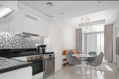 a white kitchen with a table and chairs in it at Aykon City 2 bedroom Burj view in Dubai