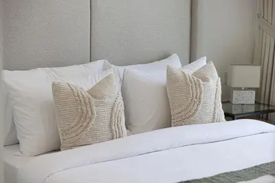 a pile of white pillows on a bed at Luxury Minimalistic Apartment in Downtown Dubai Opposite Burj Khalifa & Dubai Mall in Dubai