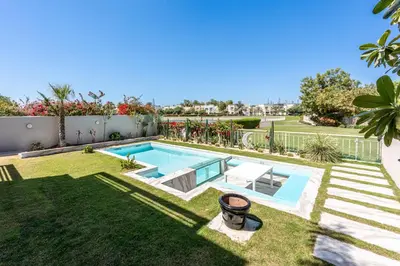 a backyard with a swimming pool and a lawn at Elegant lakeside villa with a private pool in Dubai