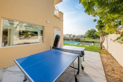 a ping pong table in the backyard of a house at Elegant lakeside villa with a private pool in Dubai