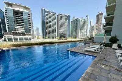 a large swimming pool in a city with tall buildings at Stunning Canal Views l Sleeps 6 in Dubai