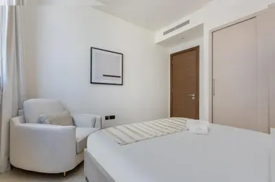 a white bedroom with a bed and a chair at STAY BY LATINEM Luxury 2BR Holiday Home CVR B1705 near Burj Khalifa in Dubai