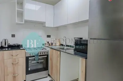 a kitchen with white cabinets and a stainless steel refrigerator at Bloomfields Cozy 1br Townhouse Life Style City in Nadd Shubayḩ