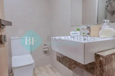 a bathroom with a white sink and a toilet at Bloomfields Cozy 1br Townhouse Life Style City in Nadd Shubayḩ