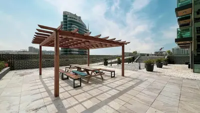 a wooden pavilion with a picnic table and a bench at LUXE | Studio in JVC | Cozy and Stylish in Dubai