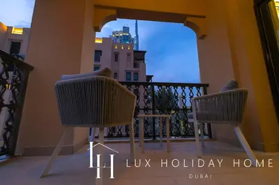 two chairs sitting on a balcony with a view of a building at LUX The Burj Khalifa View Downtown Suite in Dubai