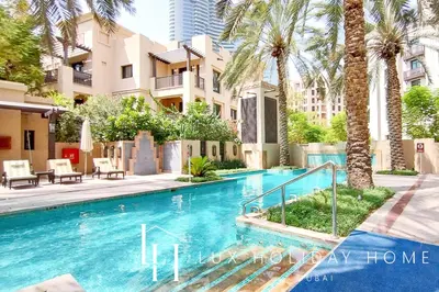 a swimming pool with palm trees and buildings at LUX The Burj Khalifa View Downtown Suite in Dubai