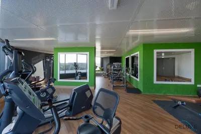 a gym with exercise equipment and green walls at Stylish Studio Apartment in Blue Wave Tower, Dubailand by Deluxe Holiday Homes in Dubai