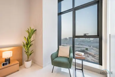 a green chair sitting in a room with a window at Stylish Studio Apartment in Blue Wave Tower, Dubailand by Deluxe Holiday Homes in Dubai