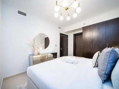 a bedroom with a large white bed and a chandelier at Sleek 2 Bed in Sports City in Dubai
