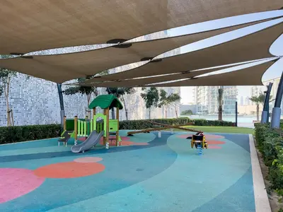 a playground with a slide and an umbrella at Spacious 1 BR Lagoon in Dubai