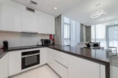 a kitchen with white cabinets and a black counter top at Spacious 1 BR Lagoon in Dubai