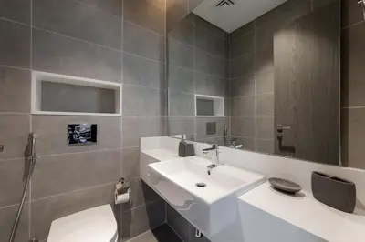 a bathroom with a sink and a toilet and a mirror at Spacious 1 BR Lagoon in Dubai