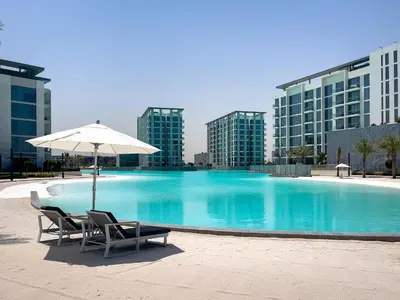 a swimming pool with two chairs and an umbrella at Spacious 1 BR Lagoon in Dubai