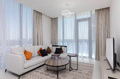 a living room with a white couch and a tv at Spacious 1 BR Lagoon in Dubai