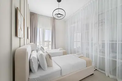 a white bedroom with two beds and a large window at Silkhaus Next Golf Club Golfville in Dubai Hills in Dubai