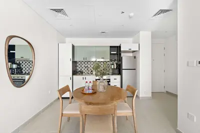 a dining room with a table and chairs and a mirror at Silkhaus Next Golf Club Golfville in Dubai Hills in Dubai
