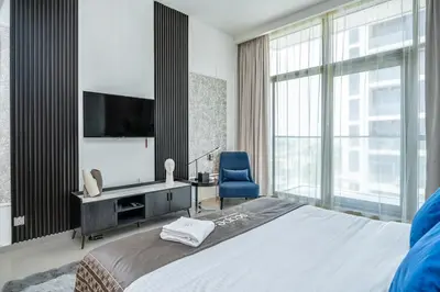 a bedroom with a bed and a tv and a chair at Escape24 Premium Studio in Damac Hills in Dubai