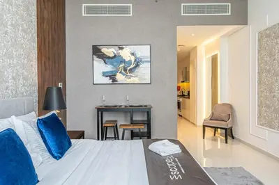 a bedroom with a bed with blue pillows and a table at Escape24 Premium Studio in Damac Hills in Dubai