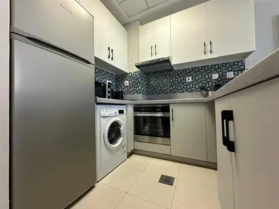 a kitchen with white cabinets and a washer and dryer at A stylish studio apartment so close to beach in Dubai