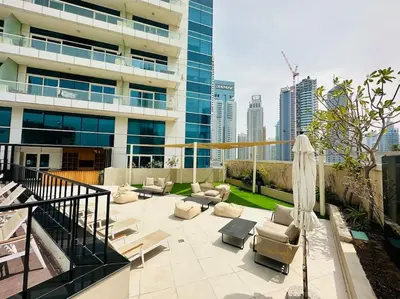 a patio with chairs and an umbrella and a building at A stylish studio apartment so close to beach in Dubai