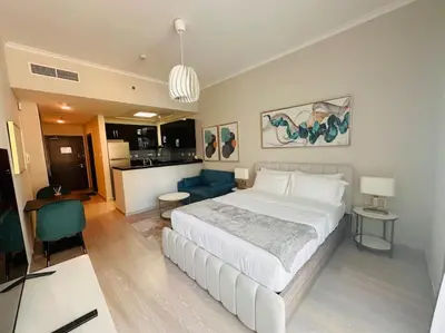 a bedroom with a large white bed and a kitchen at A stylish studio apartment so close to beach in Dubai