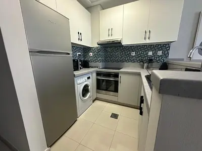 a kitchen with white cabinets and a washer and dryer at A stylish studio apartment so close to beach in Dubai