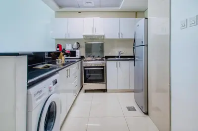 a kitchen with white cabinets and a washer and dryer at ShoresInn - Outdoor Retreat with Private Terrace in Dubai