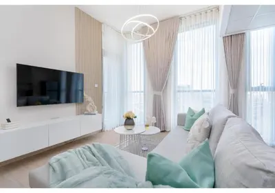 a white living room with a couch and a tv at Bright and Modern 1BR Midtown Near Expo Site by Vibel in Dubai