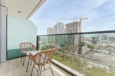 a balcony with two chairs and a table and a large window at Stylish 1BR in JVC with Pool & Nearby Parks in Dubai
