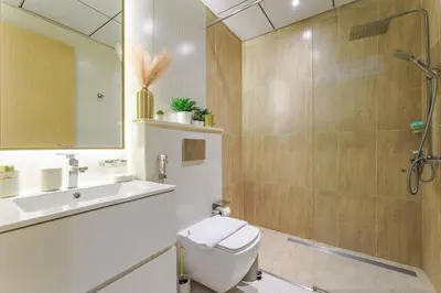 a bathroom with a shower and a toilet and a sink at Stylish 1BR in JVC with Pool & Nearby Parks in Dubai