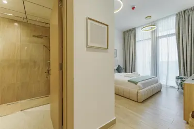 a bedroom with a bed and a shower in a room at Stylish 1BR in JVC with Pool & Nearby Parks in Dubai