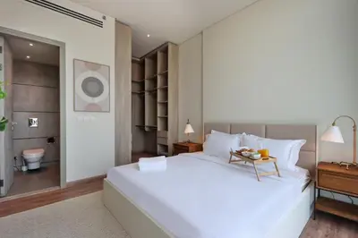 a bedroom with a large white bed and a bathroom at Livbnb - Stay at Signature Livings Penthouse, JVC in Dubai