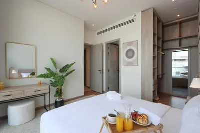 a bedroom with a white bed and a tray of fruit on a table at Livbnb - Stay at Signature Livings Penthouse, JVC in Dubai
