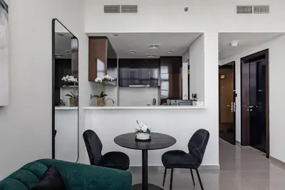 a living room with a table and chairs and a kitchen at Stylish 1BR Apartment at DAMAC Merano Tower with Great View in Dubai